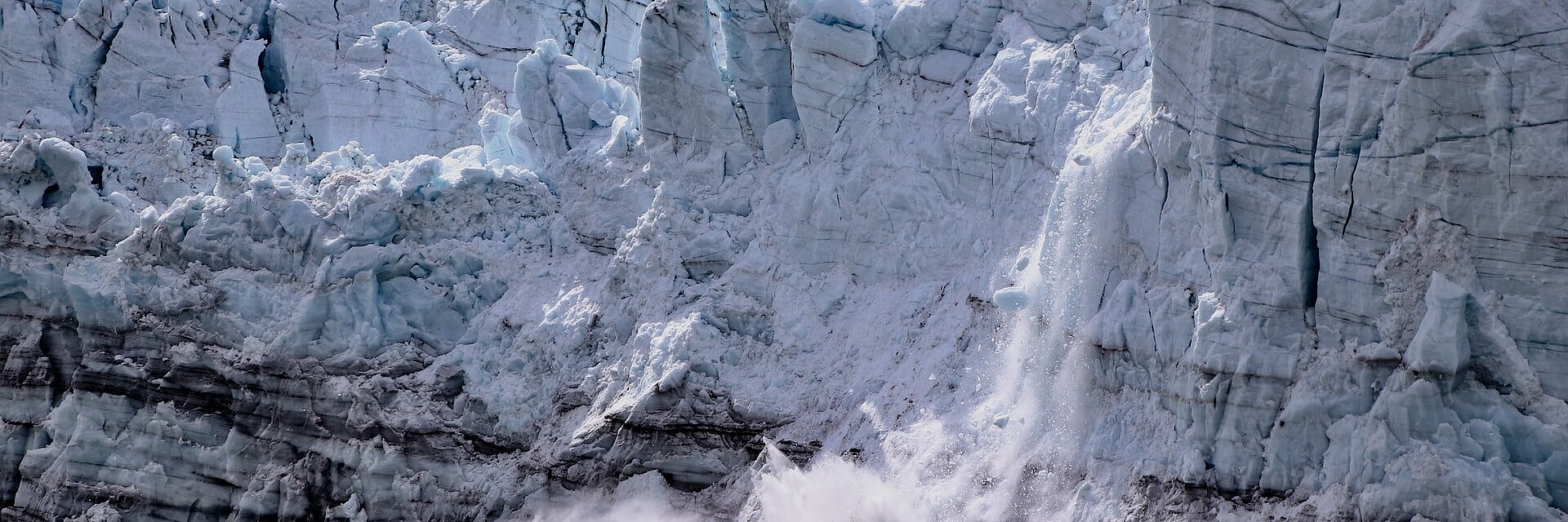 Eis bricht von einem Gletscher ab und fällt ins Wasser