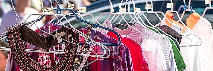 Kleidung hängt auf Kleiderhaken an einer Kleiderstange Kleidung hängt auf Kleiderhaken an einer Kleiderstange