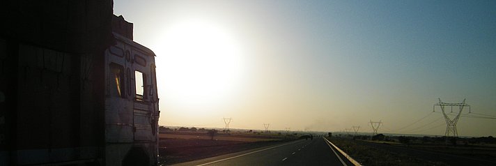 LKW fährt auf der Autobahn dem Sonnenaufgang entgegen