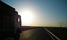 LKW fährt auf der Autobahn dem Sonnenaufgang entgegen