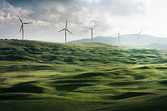 Blick auf Windrädern hinter Ackerflächen